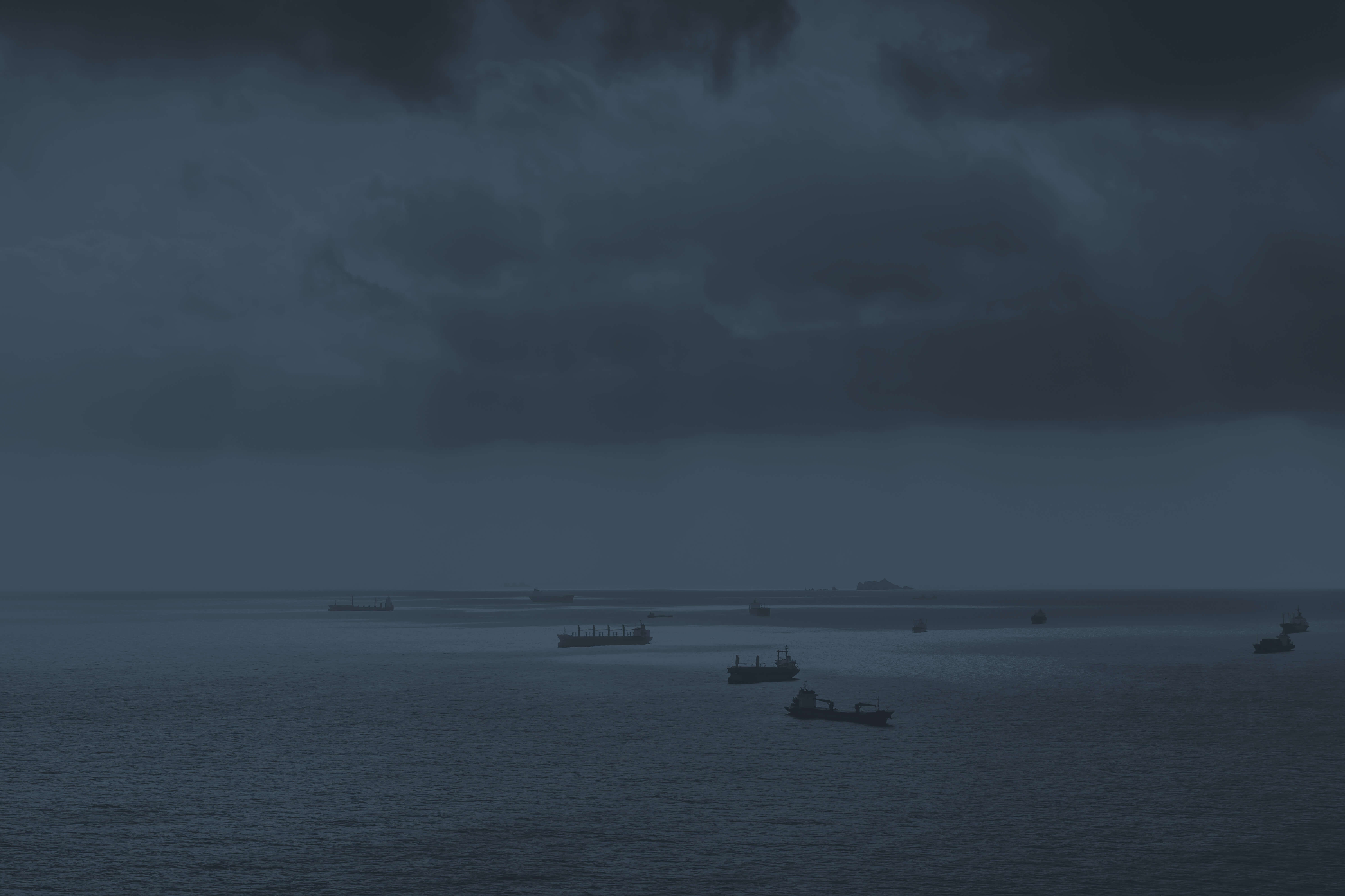 Imagem de fundo, vários návios sobre o mar, esta em tons de cinza chumbo.